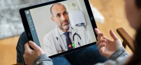 Personne tenant une tablette entre les mains et faisant une visioconférence avec un médecin