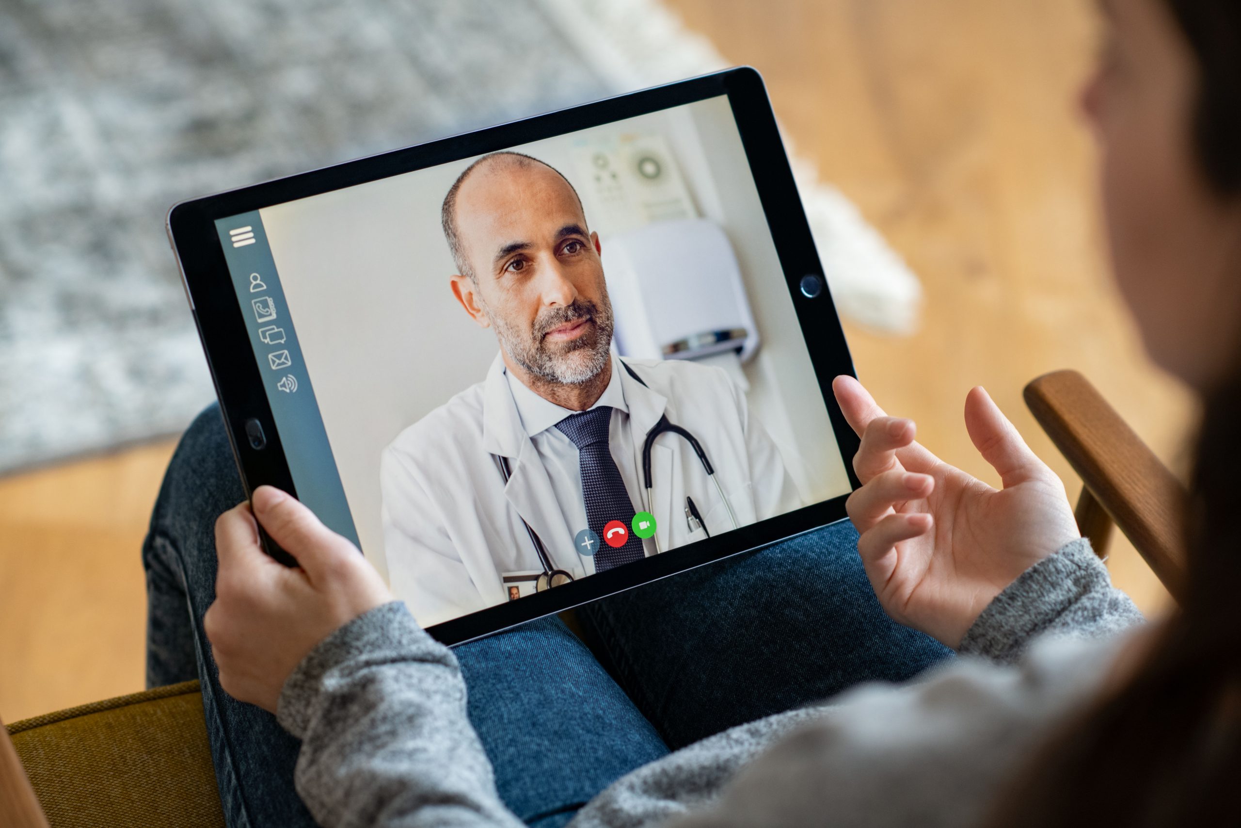 Personne tenant une tablette entre les mains et faisant une visioconférence avec un médecin