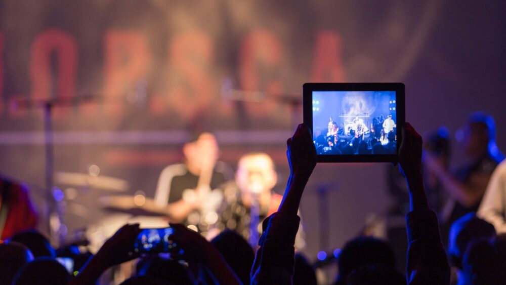 salle de concert avec une personne qui filme avec un ipad