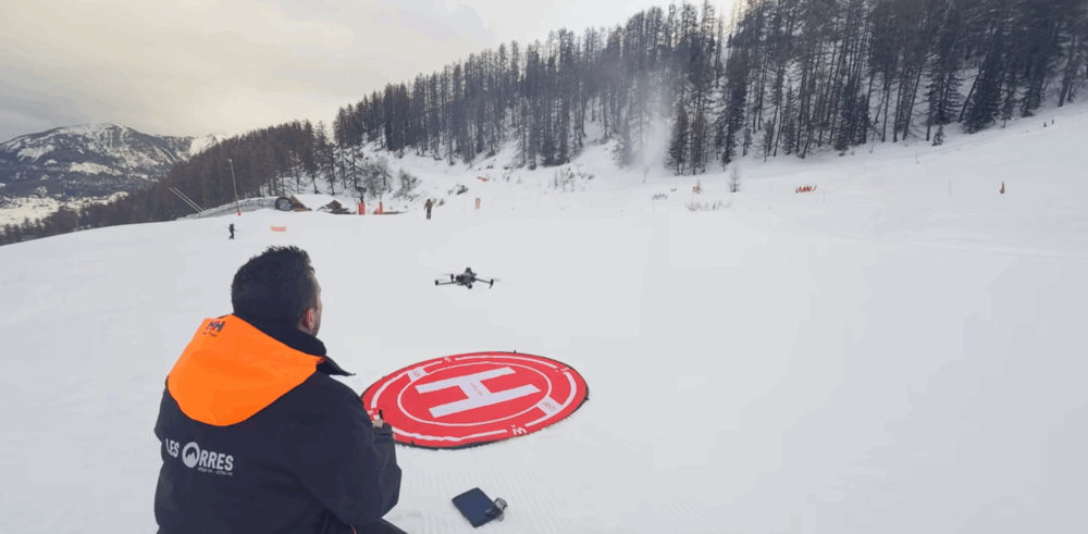 Image des Orres avec un technicien conduisant un drone au dessus d'une piste de ski